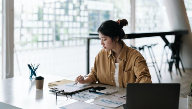 Accountant business woman using calculator and computer laptop, budget and loan paper in office