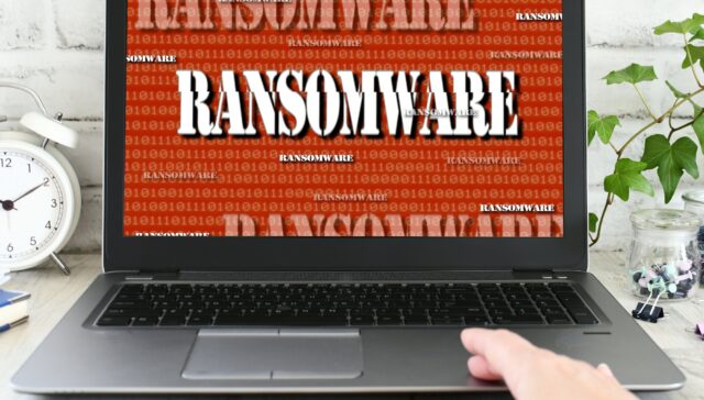 Person working on a laptop computer that has been seized by a ransomware cyber attack. hacked virus