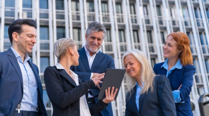 Senior Executives Exchange Ideas with Tablet in Commercial Building Office
