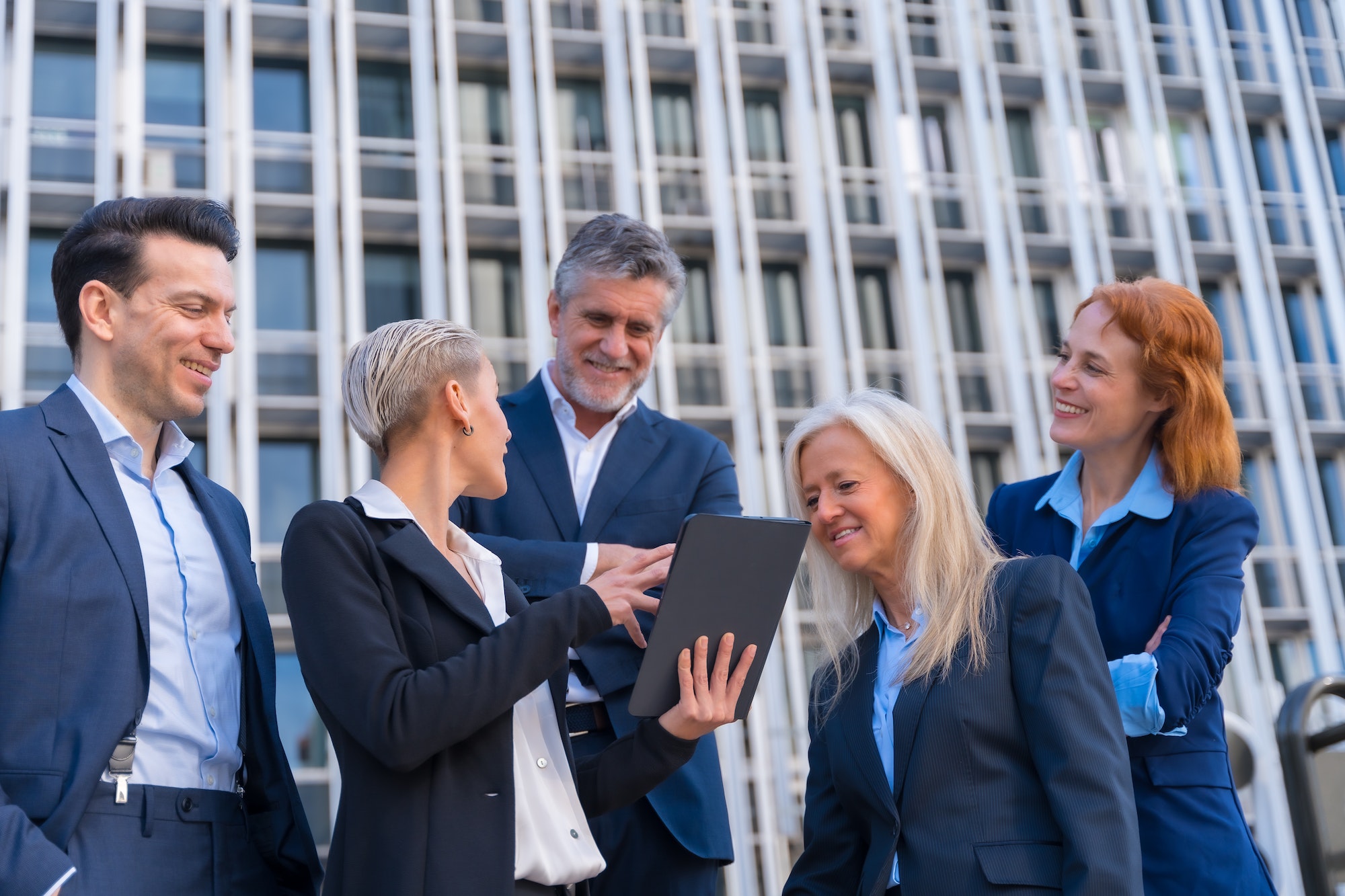 Senior Executives Exchange Ideas with Tablet in Commercial Building Office