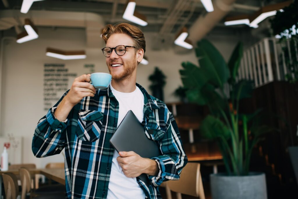 Young guy drinking tea or coffee in office space