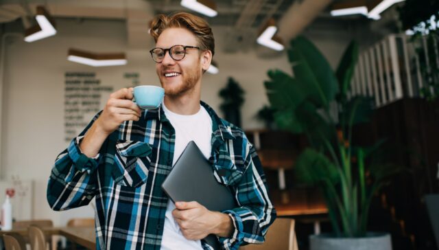 Young guy drinking tea or coffee in office space