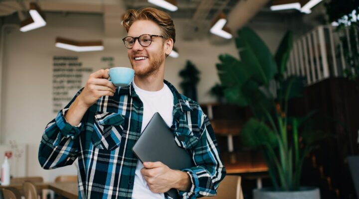 Young guy drinking tea or coffee in office space